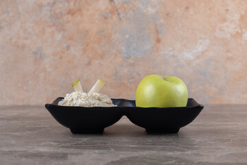 Grated rice cake and apple in the bowl, on the marble background