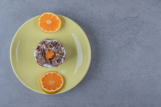 Fresh creamy muffin with orange slices on yellow plate