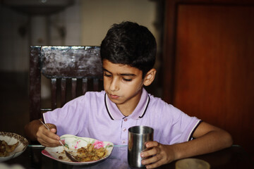 Fototapeta na wymiar Boy having meal on dinning table at home
