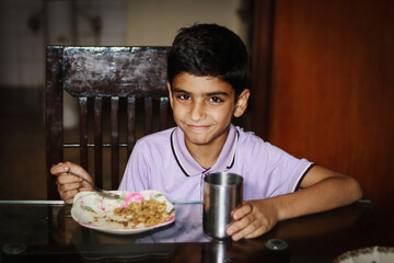 Fototapeta na wymiar Boy having meal on dinning table at home