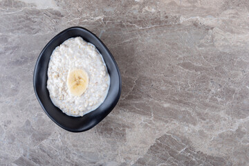 Ripe sliced banana on a bowl of porridge, on the marble background