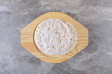 Oat porridge in wooden plate, on the marble background