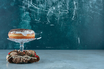 A glass plate with doughnut and a Christmas wreath