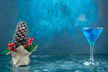 A big Christmas pinecone with a glass cup of blue drink