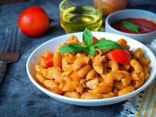 Macaroni pasta with tomato sauce in white plate on grey color table