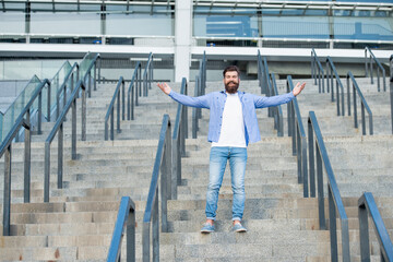 happy bearded man downstairs. full length of man with beard. hipster man outdoor at stairs