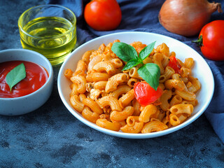 Macaroni pasta with tomato sauce in white plate on grey color table