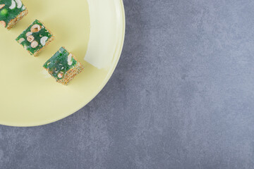 Top view if Turkish delight rahat lokum with hazelnuts on yellow plate