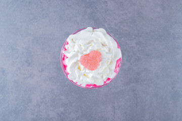 Freshly made creamy pink milk shake on grey background