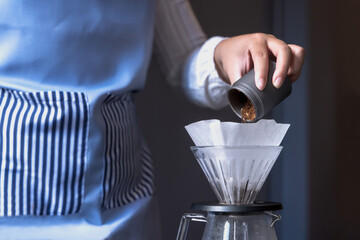 Close up barista hands pouring ground coffee into paper filter and making espresso coffee in coffee shop, Coffee Barista Concept