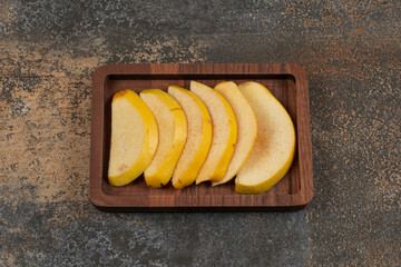 Ripe sliced quince on wooden plate