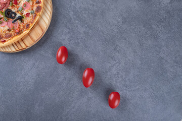 Top view of pepperoni pizza on wooden board with tomatoes