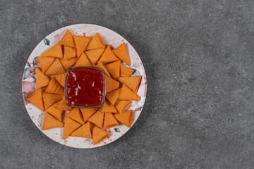 Triangle shaped crackers on plate with ketchup