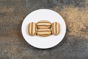Delicious chocolate striped biscuits on white plate