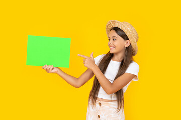 happy teen girl with copy space on green paper on yellow background. point finger