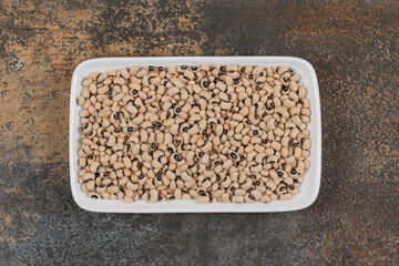 Pile of raw white beans on white plate