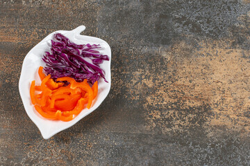 Shredded purple cabbage and pepper on white plate