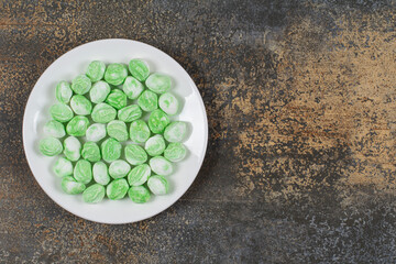 Green menthol candies on white plate