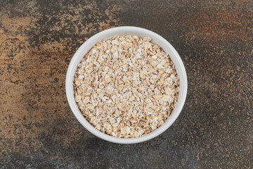 Dry oat flakes in white bowl