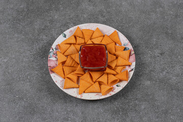 Triangle shaped crackers on plate with ketchup