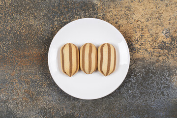 Delicious chocolate striped biscuits on white plate