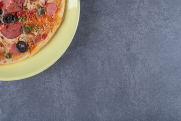 Freshly baked pepperoni pizza on yellow plate over grey background