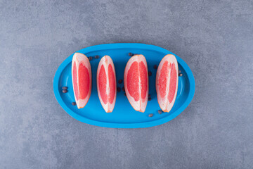 Top view of fresh grapefruit slices on blue wooden board