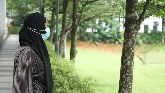  thoughtful muslim woman with flu mask looking away 