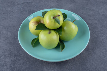 Pile of fresh green apple on blue plate