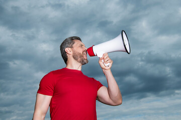 man in red shirt speak in loudspeaker on sky background