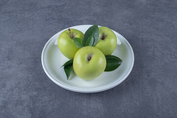 Three fresh green apple on white plate