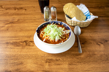 Pozole is a traditional mexican soup made with corn, pork and spices. It's garnished with lettuce...
