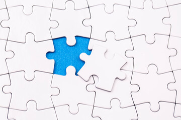 Missing jigsaw puzzle pieces. Business concept. Fragment of a folded white jigsaw puzzle and a pile of uncombed puzzle elements against