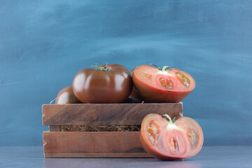 Fresh whole and sliced tomatoes in wooden box