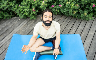 Hispanic man with leg prosthesis in sportswear doing yoga asana outdoors. Disabled sport concept