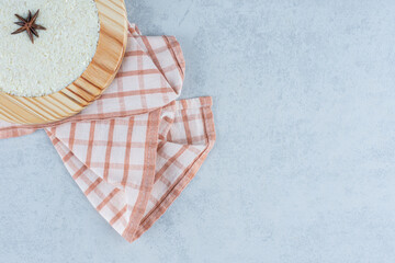 Fototapeta na wymiar Cinnamon on oat porridge in wooden plate, on towel, on the marble background