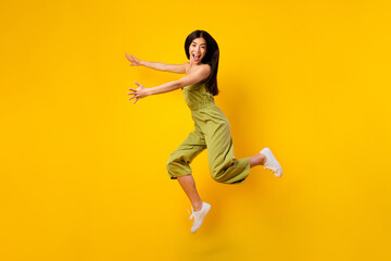 Fototapeta na wymiar Full length photo of overjoyed excited girl jump arms catch empty space isolated on yellow color background