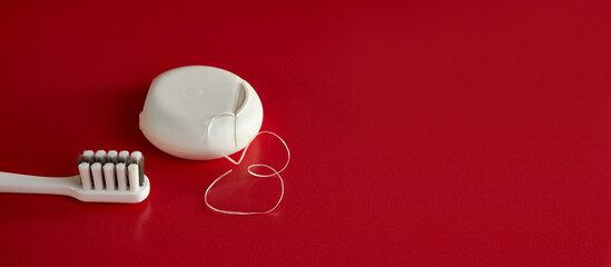 Dental floss and toothbrush on a red background. Dental care.