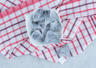 A bowl of tea bags on towel , on the marble background