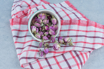 Dried Pink Rose Buds in the bowl on towel, on the marble background