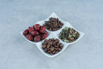 Dry leaves and dried rose hips on the bowl, on the marble background