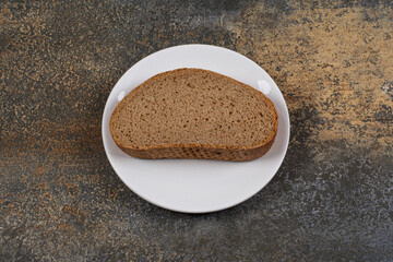 One black bread slice on white plate