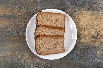 Three slices of black bread on white plate