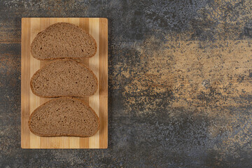 Three slices of black bread on wooden board