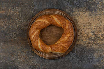 Delicious simit with sesame seeds on wooden plate