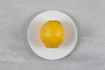 Fresh quince on the plate, on the marble background