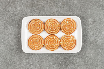 Round biscuits with sesame seeds on white square plate