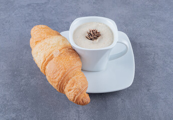 Cup of Cappuccino and croissant for breakfast on grey background
