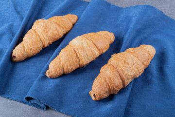 Three fresh French Croissant on blue napkin