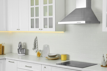 Elegant kitchen interior with modern range hood over cooktop and stylish furniture